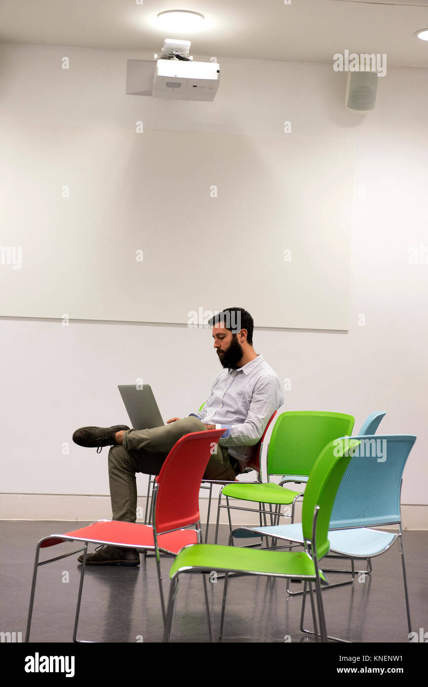 Mann sitzt auf Stuhl im Büro mit Laptop Stockfoto