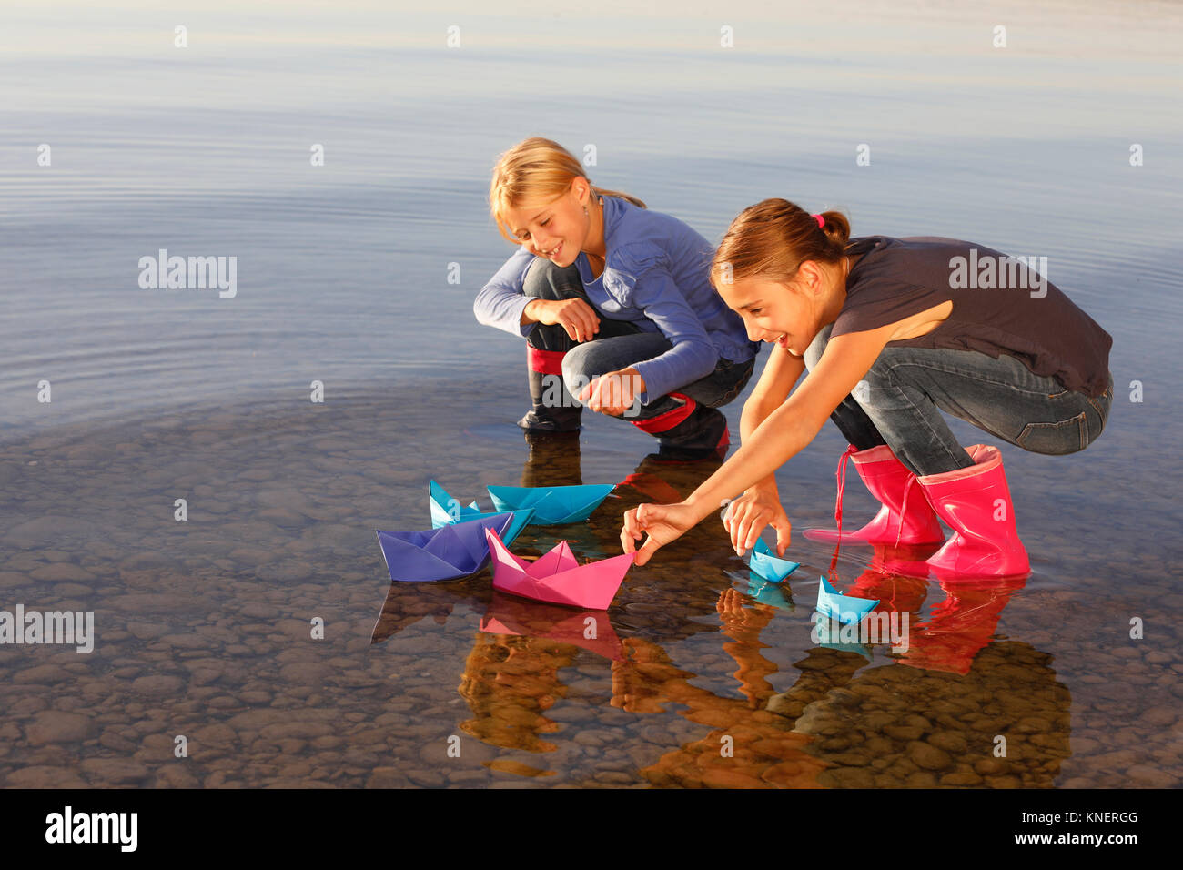 Zwei junge Mädchen floating Papier Boote auf dem Wasser Stockfoto