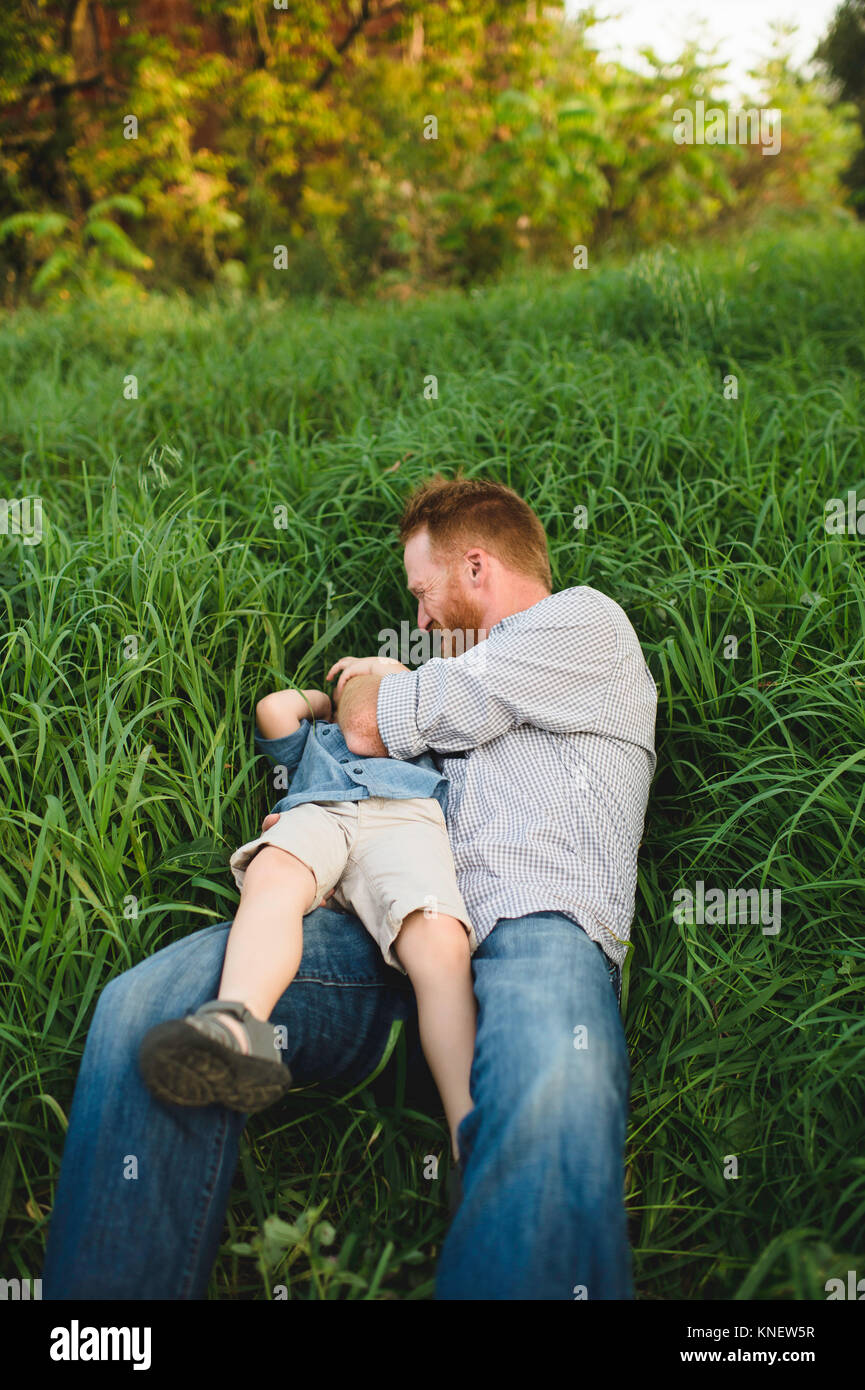 Vater kitzeln Sohn im hohen Gras Stockfoto