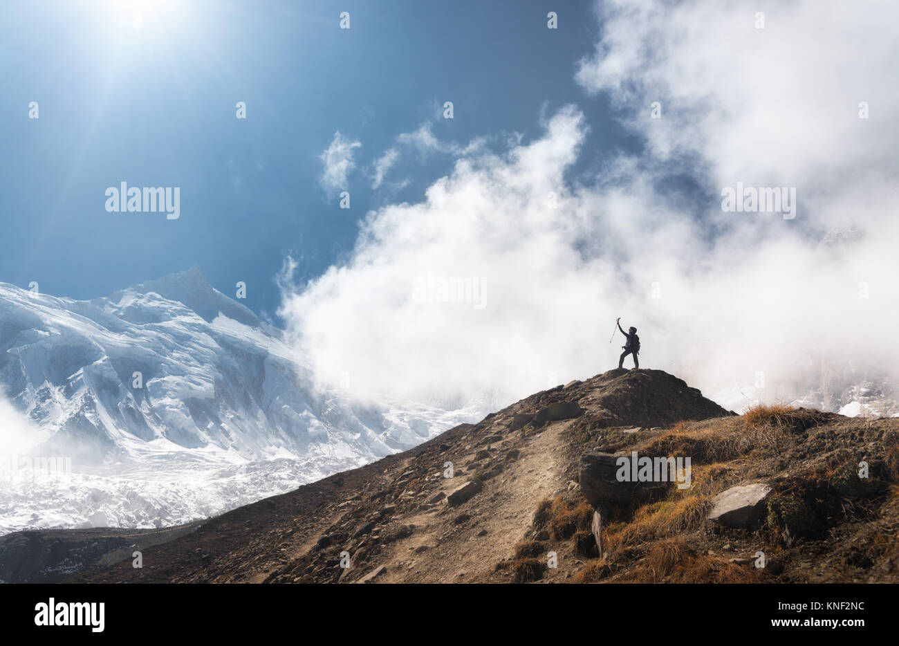 Stehende junge Frau mit erhobenen Armen auf dem Gipfel gegen den blauen Himmel mit Wolken in den hellen Tag. Landschaft mit Happy girl auf dem Hügel, s Stockfoto