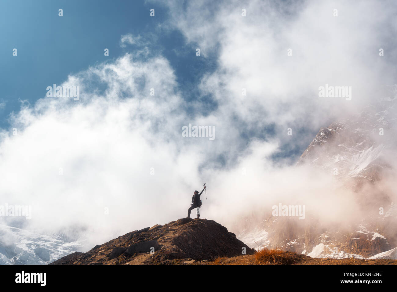 Stehende junge Frau mit erhobenen Armen auf dem Gipfel gegen den blauen Himmel mit Wolken in den hellen Tag. Landschaft mit Happy girl auf dem Hügel, s Stockfoto