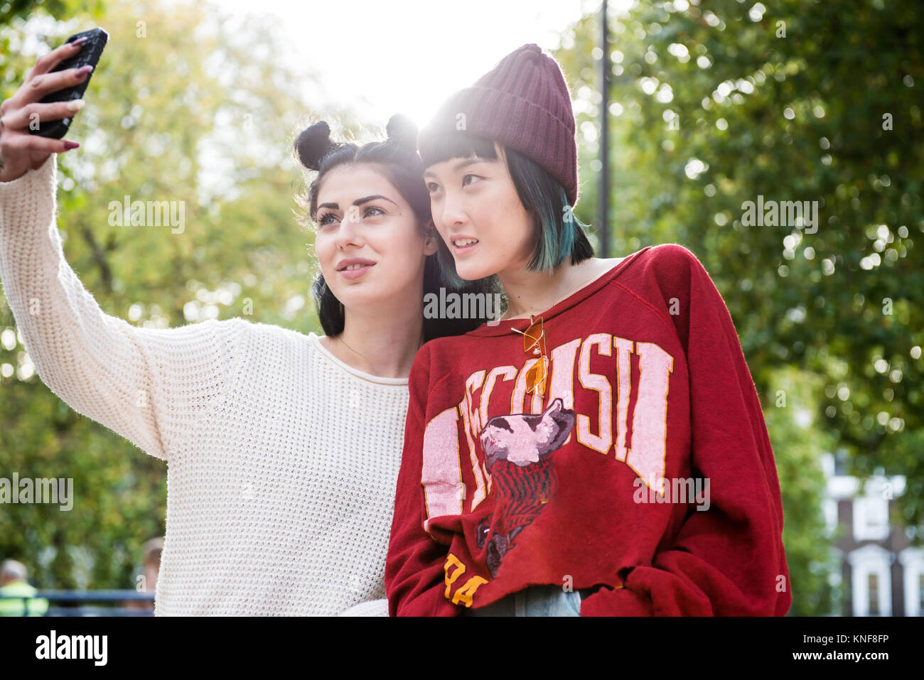 Zwei junge Frauen, die elegante Smartphone selfie im City Park Stockfoto