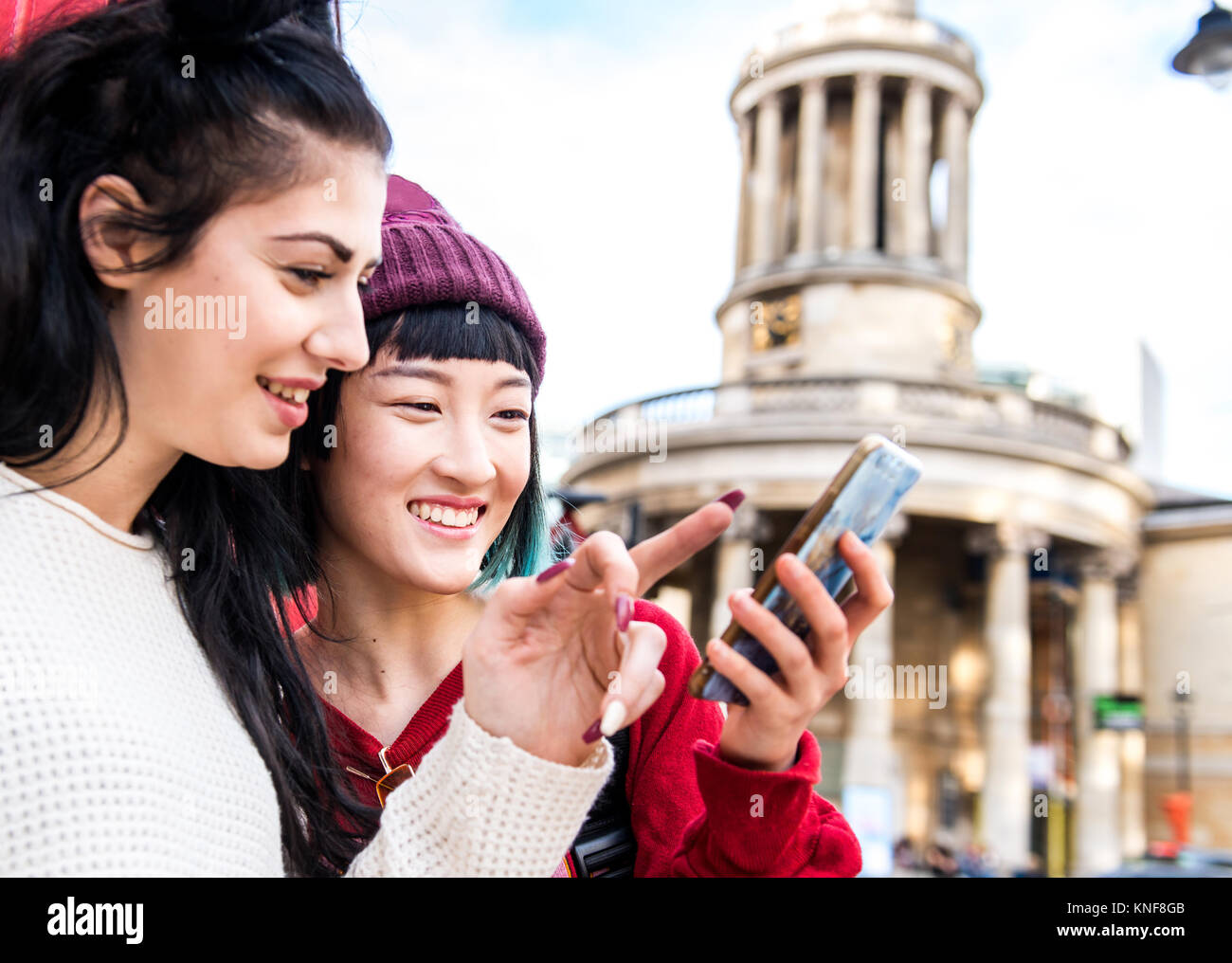 Zwei junge stilvolle Frauen auf Smartphone, London, UK suchen Stockfoto