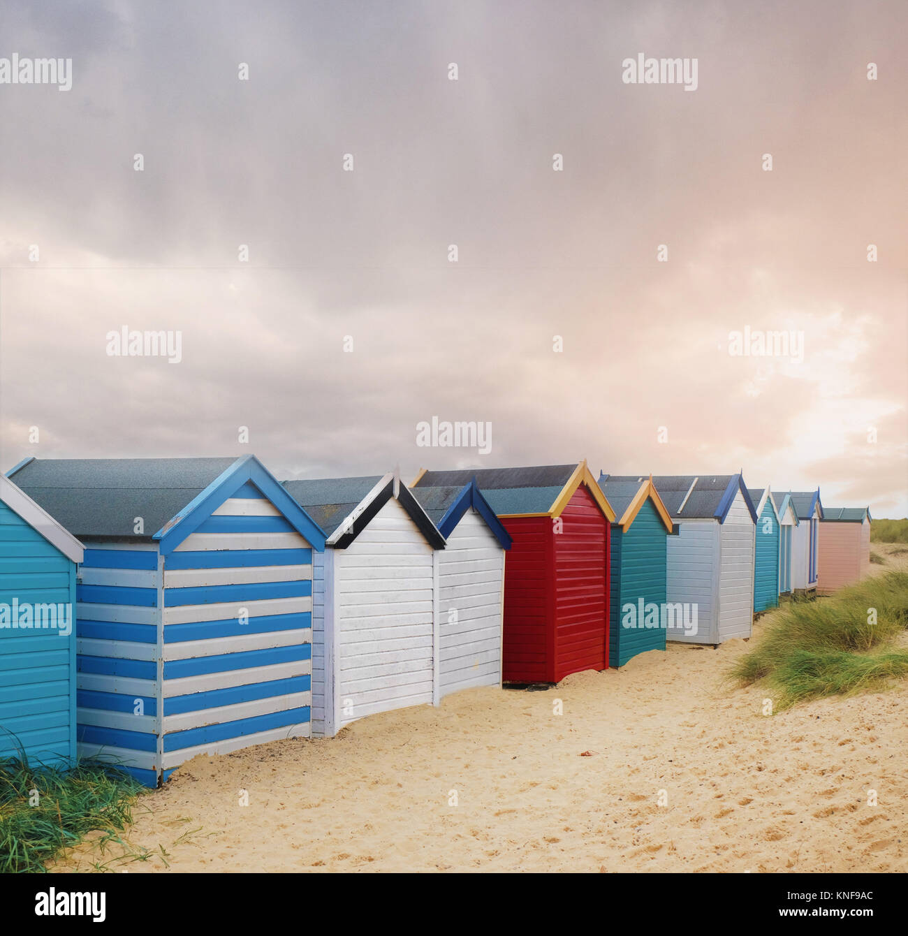 Reihe von bunten Badekabinen und Gewitterwolken, Southwold, Suffolk, England Stockfoto