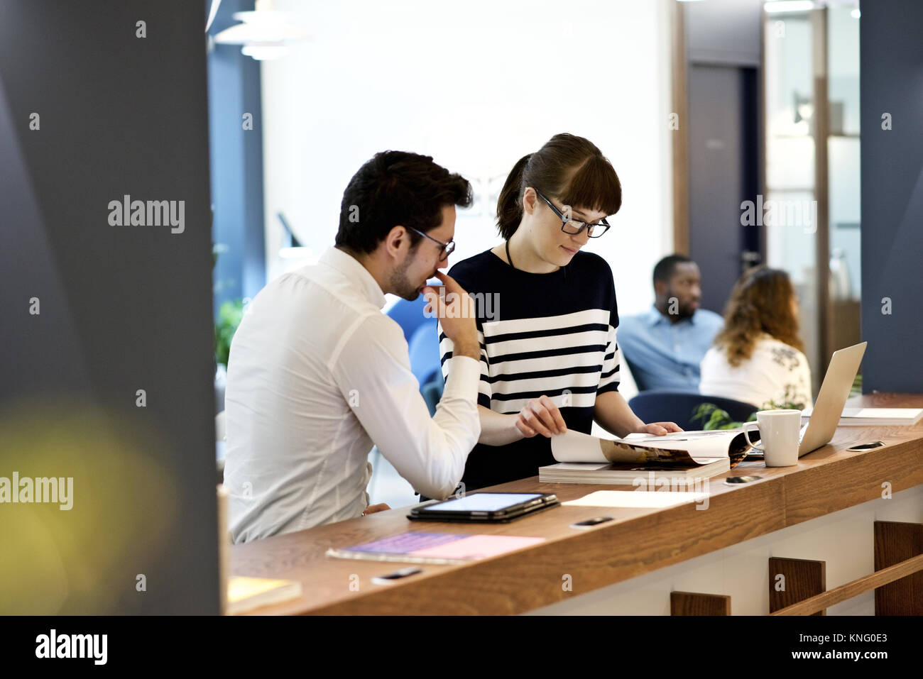 Kaukasische Frauen Business Leader mit kaukasischen männlichen Kollegen lesen in eine kreative Agentur Büro Stockfoto
