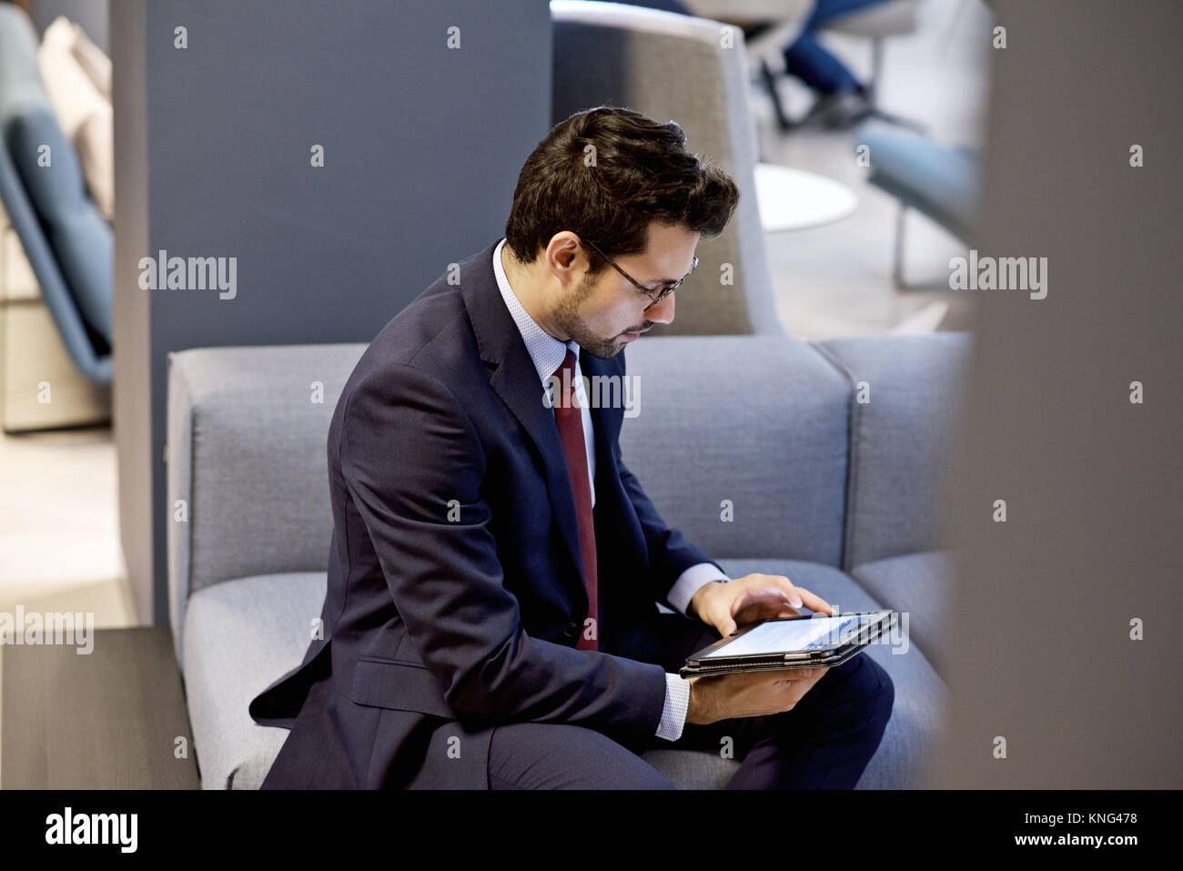 Kaukasische Geschäftsmann in einem eleganten Anzug mit einem mobilen Tablet-Gerät in einem modernen Interieur gestaltet Amt bekleidet Stockfoto