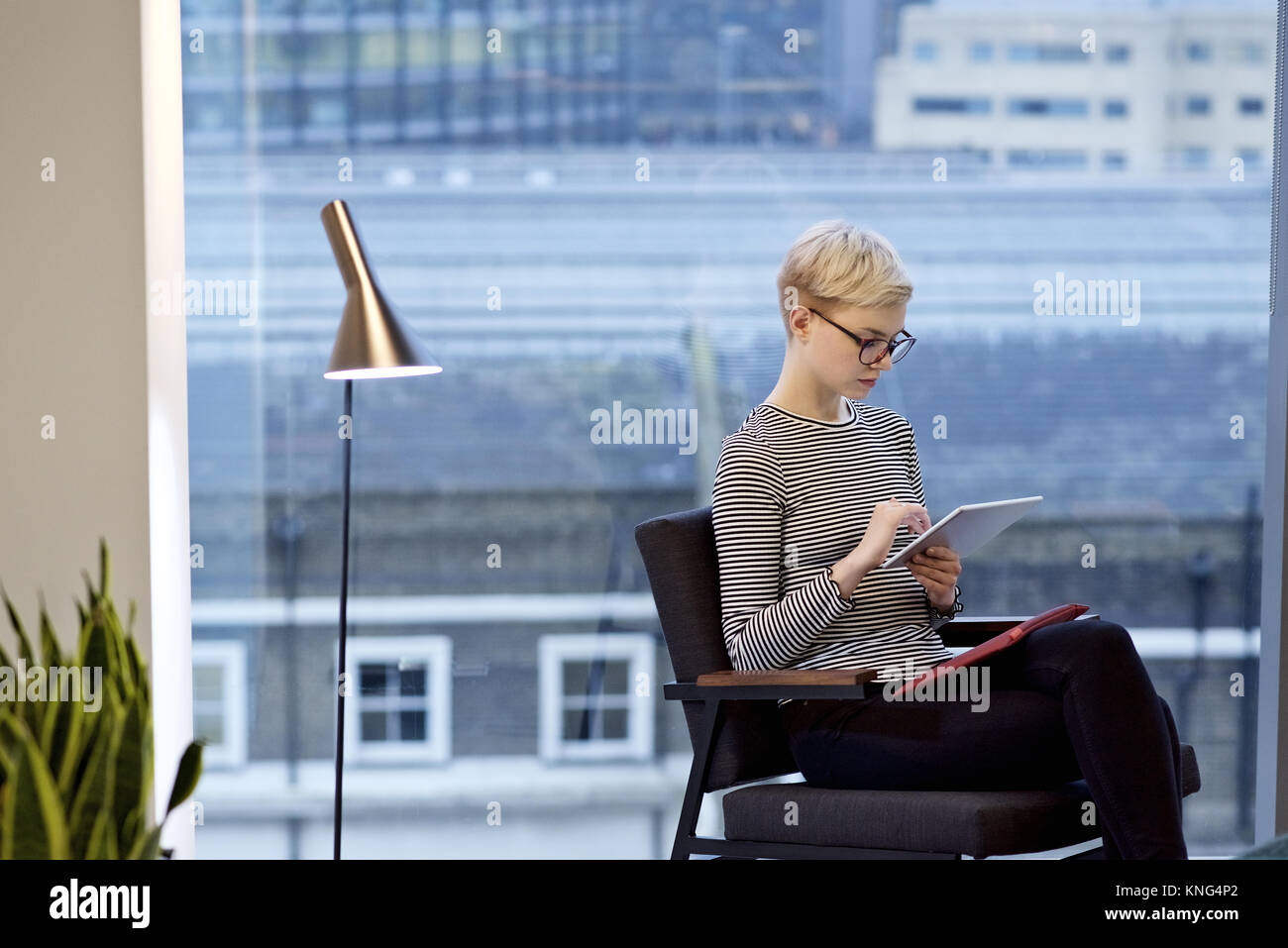 Kaukasische Geschäftsfrau in einem modernen Büro auf den Bildschirm tippen, von einem mobilen Gerät Stockfoto