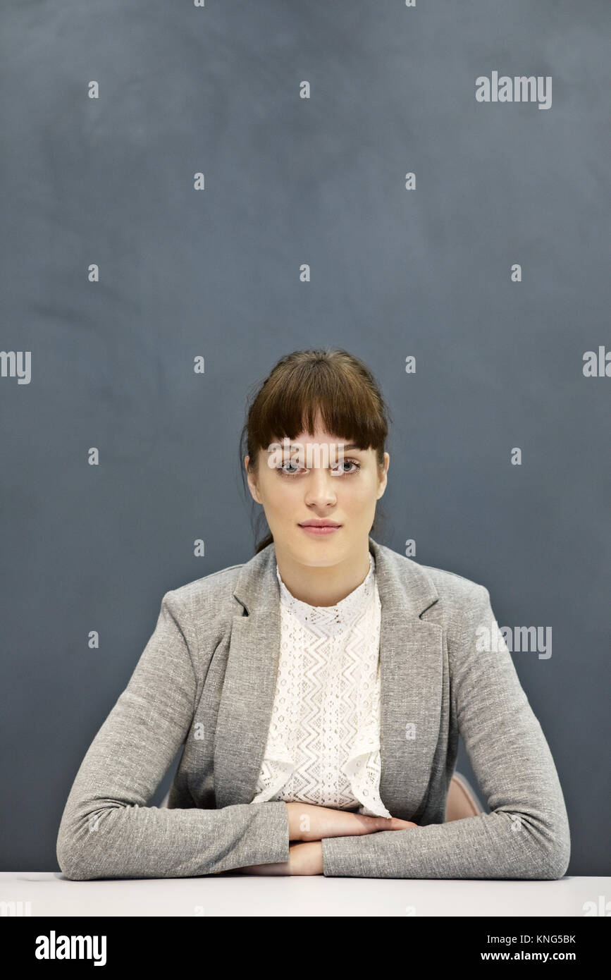 Porträt eines stolzen und entschlossene junge geschäftsfrau, sitzen mit einem schlichten grauen Hintergrund und Platz für Kopie Stockfoto