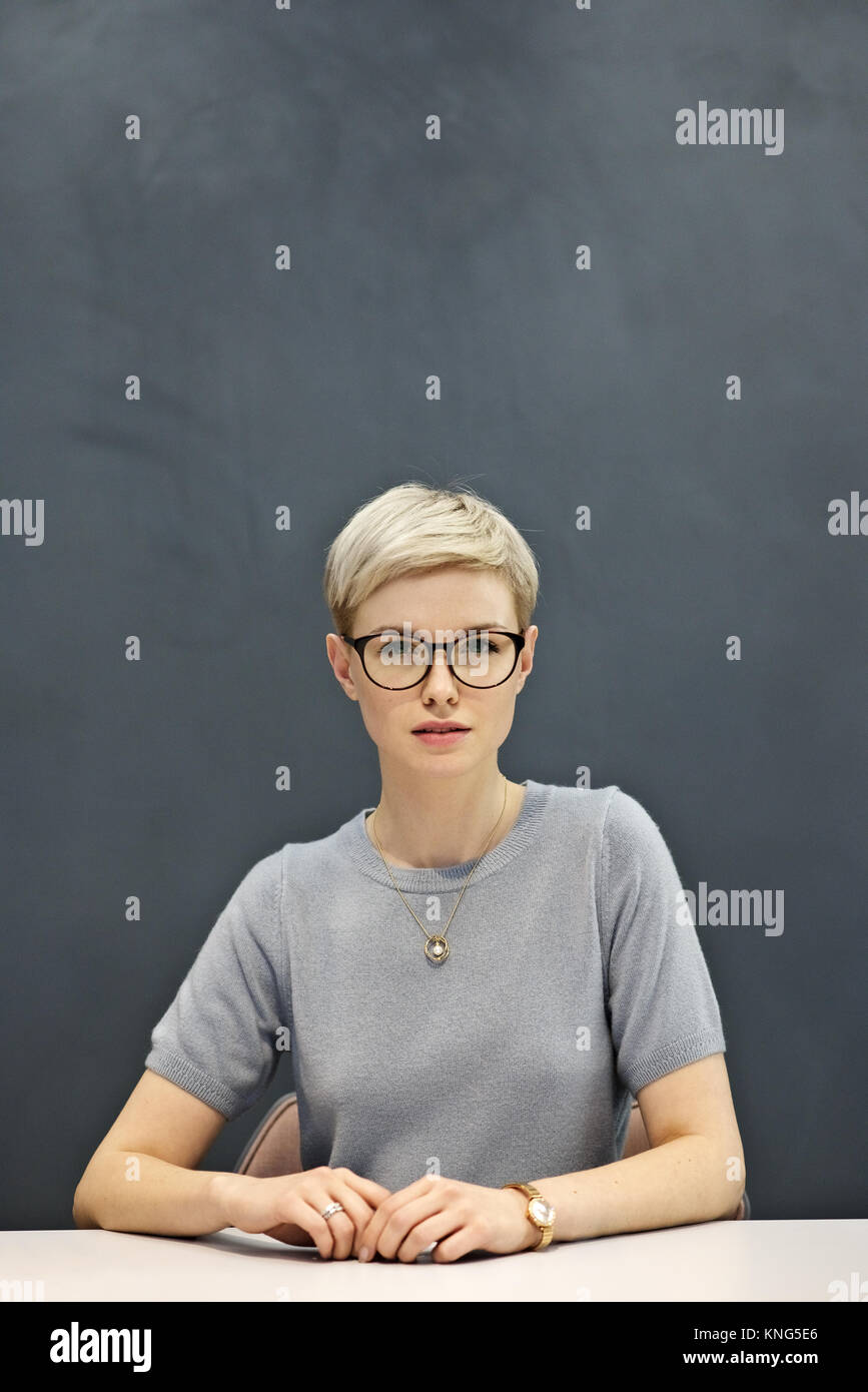 Porträt eines stolzen und entschlossene junge geschäftsfrau, sitzen mit einem schlichten grauen Hintergrund und Platz für Kopie Stockfoto