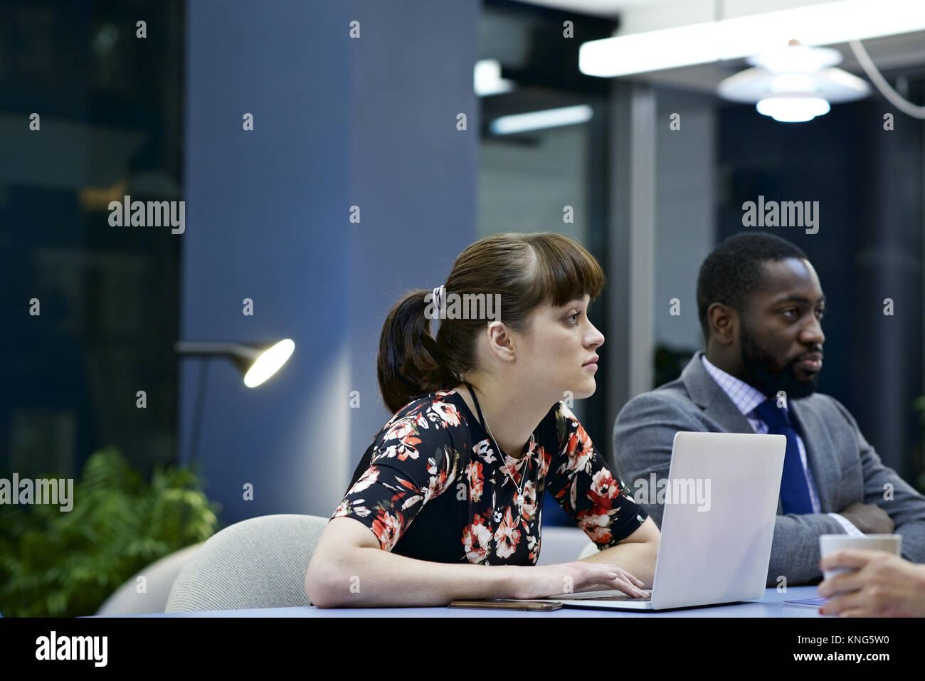 Kaukasische Geschäftsfrau mit einem Laptop und schwarze männliche Kollegen in einem Team Meeting in einem modernen Büro Stockfoto