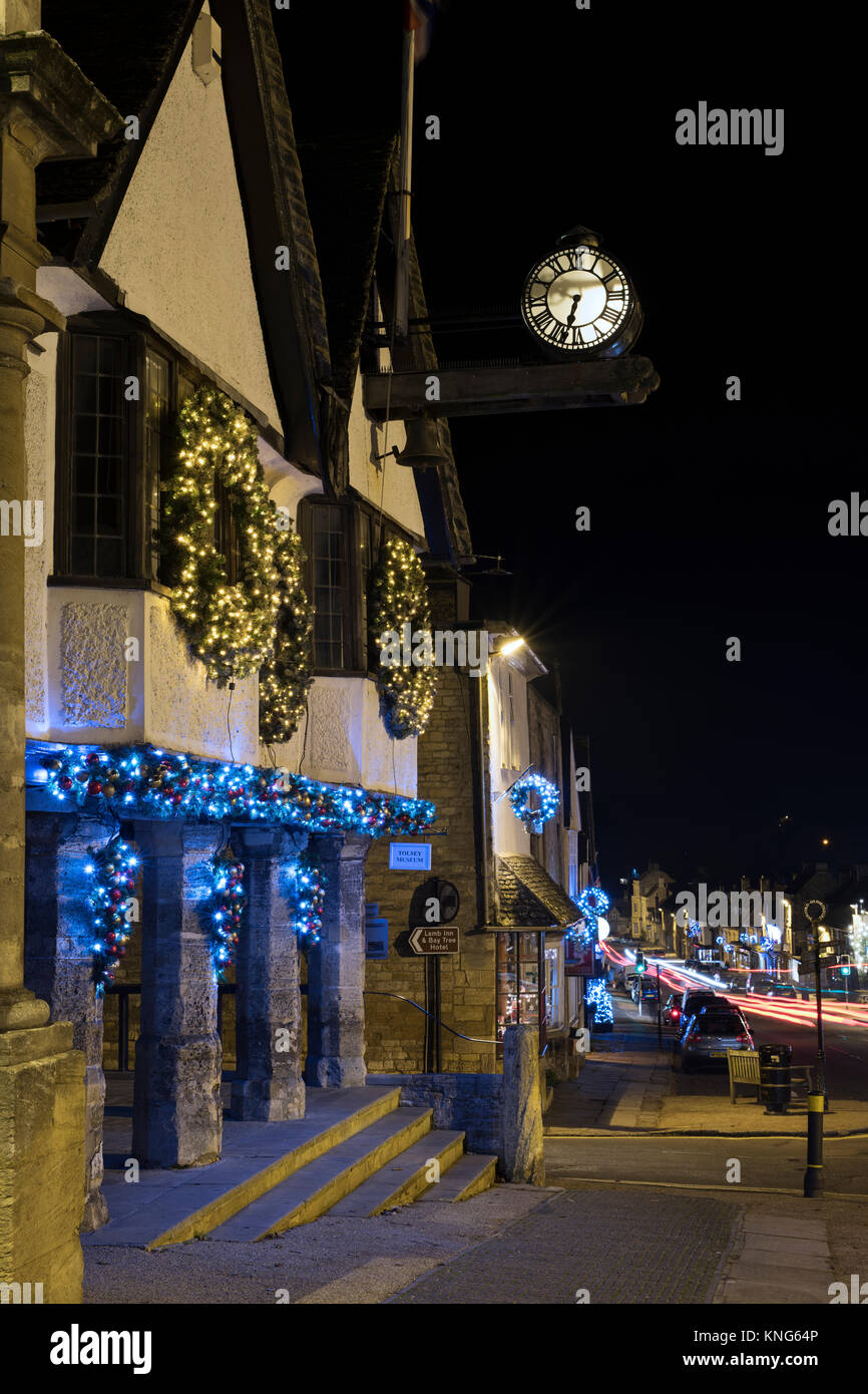 Weihnachten Kranz Dekorationen und Lichter auf dem Tolsey Museum bei Nacht. Burford, Cotswolds, Oxfordshire, England Stockfoto