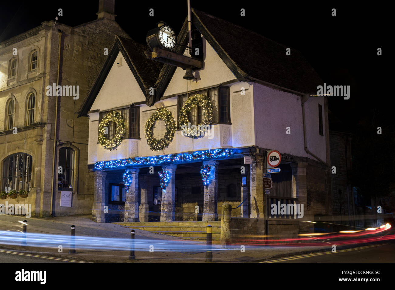 Weihnachten Kranz Dekorationen und Lichter auf dem Tolsey Museum bei Nacht. Burford, Cotswolds, Oxfordshire, England Stockfoto