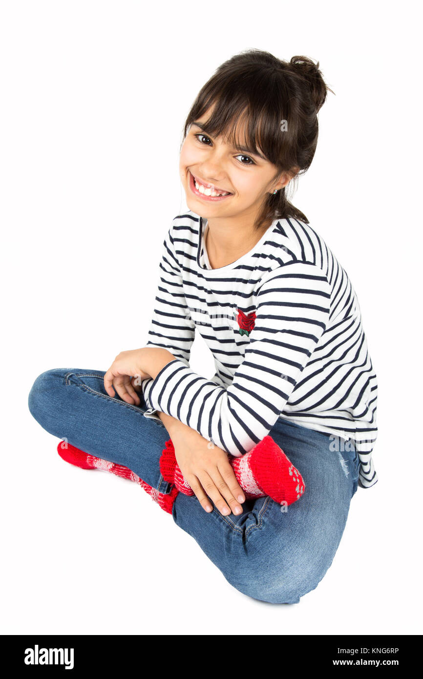 Porträt der kleinen, glücklichen Mädchen in gestreiften T-Shirt und eine blaue Jeans und rote Socken auf dem Boden saß. Auf weiß Isoliert Stockfoto