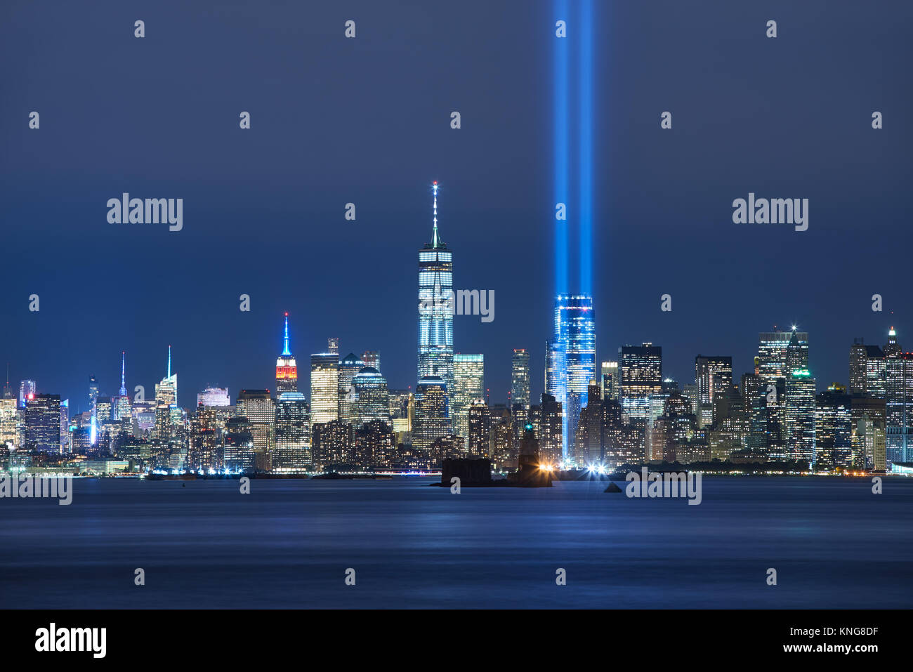 Die beiden Balken des Tribute in Light mit Wolkenkratzern von Lower Manhattan bei Nacht von New York Harbor. Financial District, New York City Stockfoto