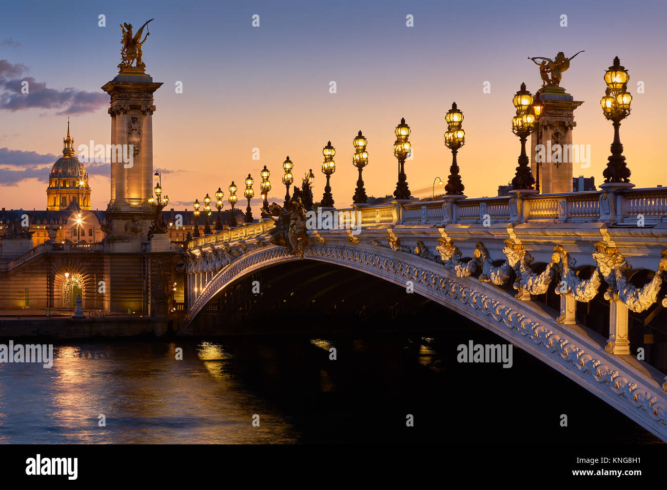 Pont Alexandre III Brücke und beleuchteten lampe Beiträge bei Sonnenuntergang mit Blick auf den Invalidendom. 7. Arrondissement, Paris, Frankreich Stockfoto