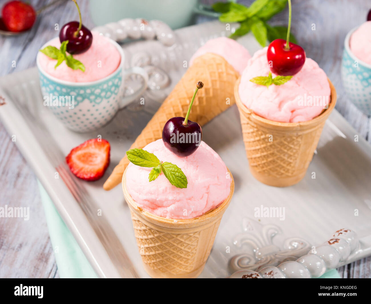 Hausgemachte Erdbeere und Kirsche Eis in der Waffel Lagerringe und -kegel auf einem keramischen Fach Vintage Stimmung serviert. Stockfoto