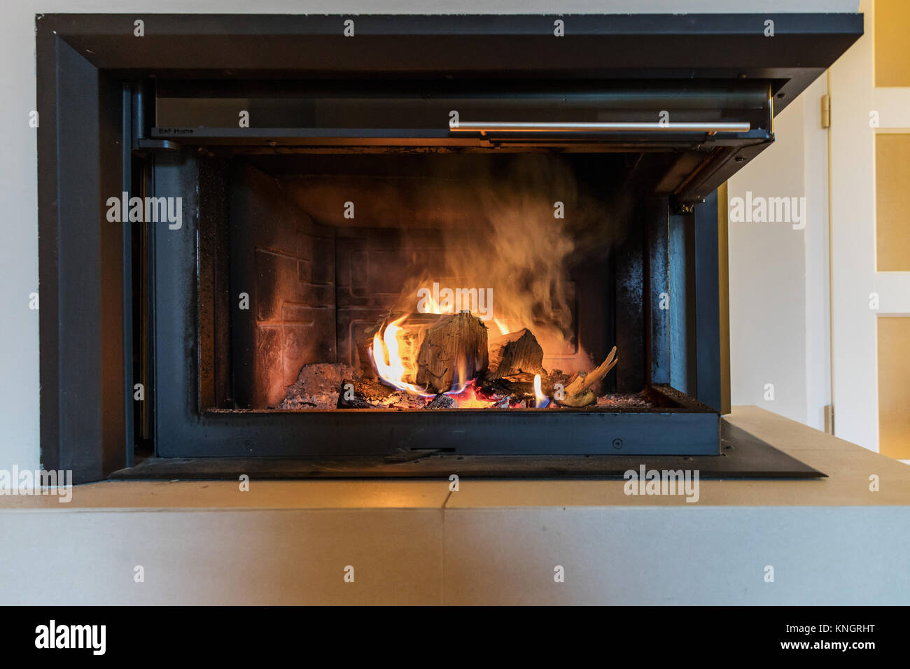 Kamin in einem modernen Haus. Das Verbrennen von Holz in den Kamin. Nahaufnahme auf die Füße. Winter- und Weihnachtsferien Konzept. Stockfoto