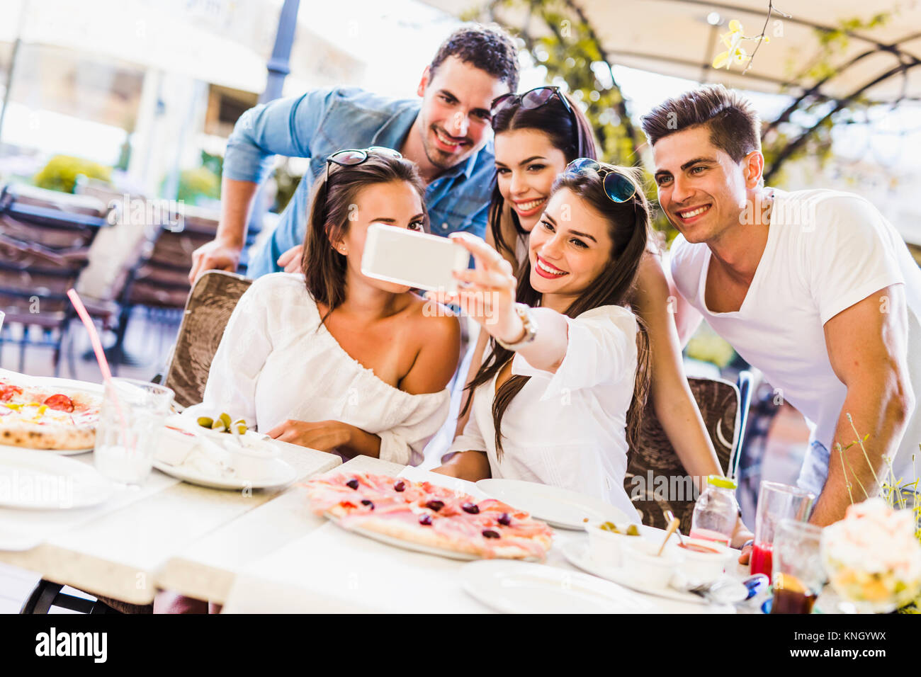 Gruppe junge schöne Menschen sitzen in einem Restaurant und Taki Stockfoto