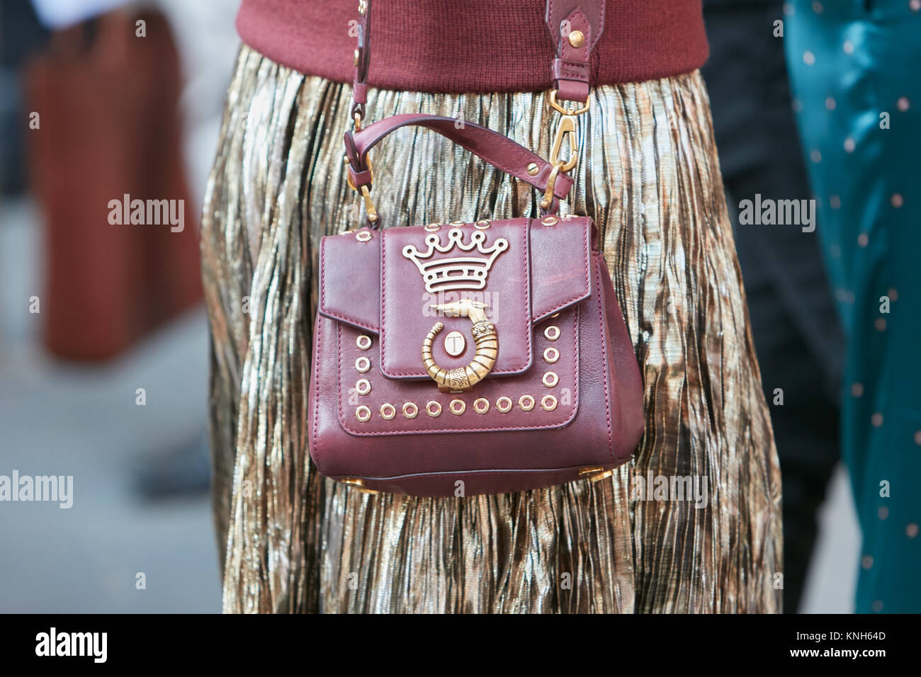 Mailand - 24. SEPTEMBER: Frau mit braun rot Leder Tasche und golden Faltenrock vor Trussardi fashion show, Mailand Fashion Week street style Sept Stockfoto