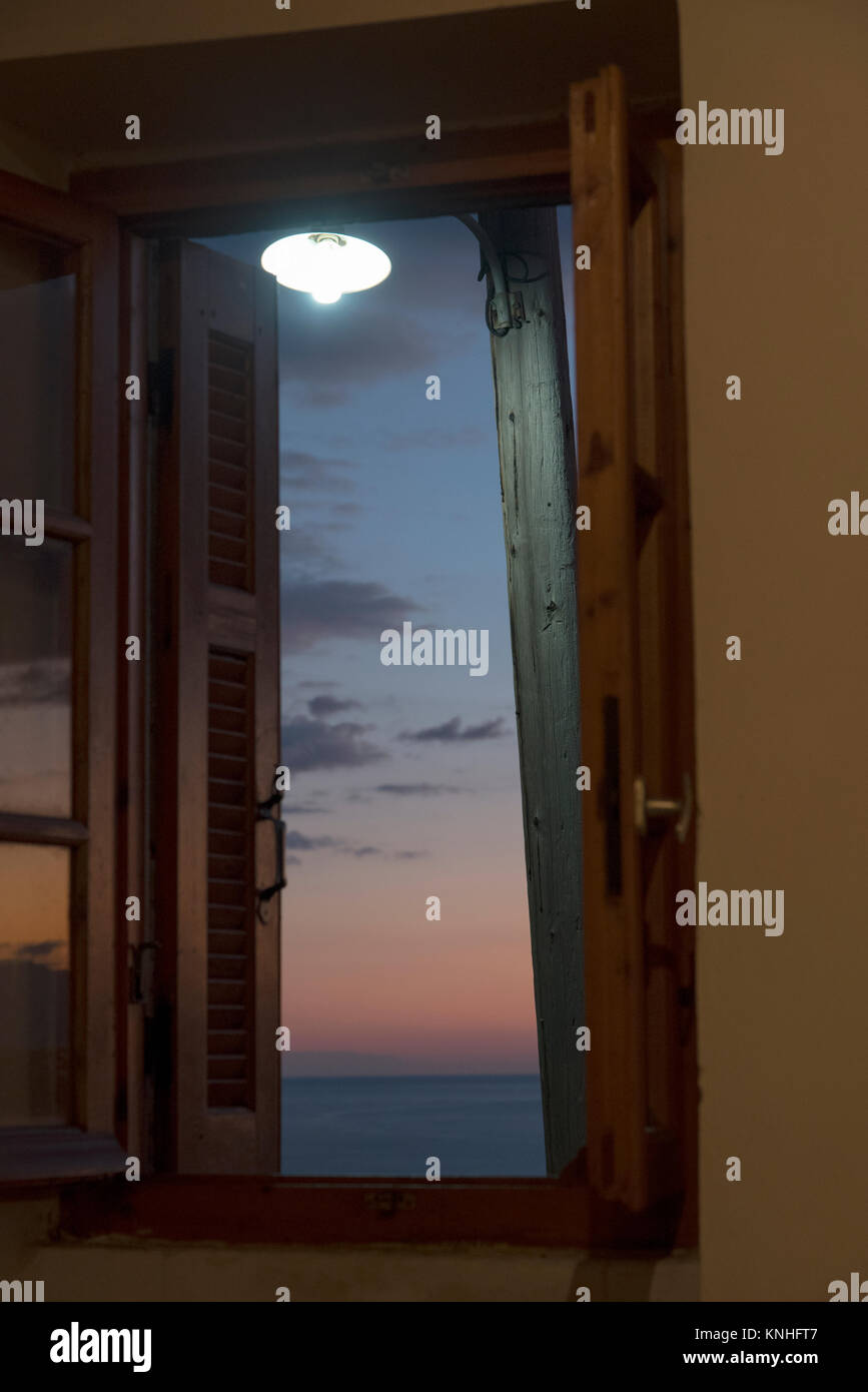 Straße Licht durch ein Fenster gegen einen stimmungsvollen Sonnenuntergang am Mittelmeer im Süden Griechenlands Stockfoto