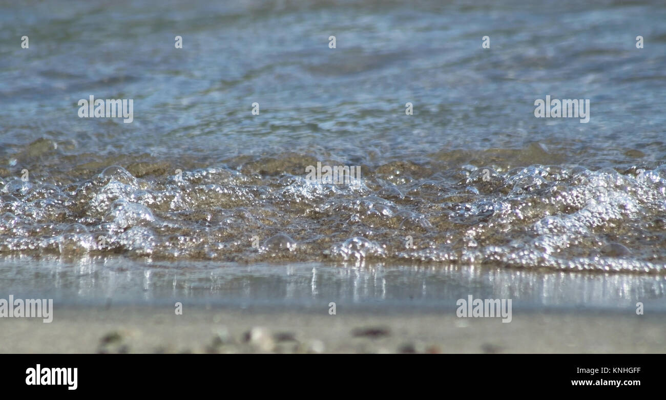 Wasser rollt zum Sandstrand Kante auf Augenhöhe Stockfoto