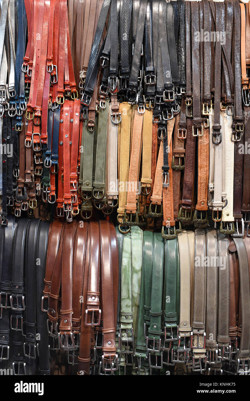 Sortierte Leder Gürtel in verschiedenen Farben für den Verkauf in einem Laden hängen über drei Schienen in einem full frame Hintergrund anzeigen Stockfoto