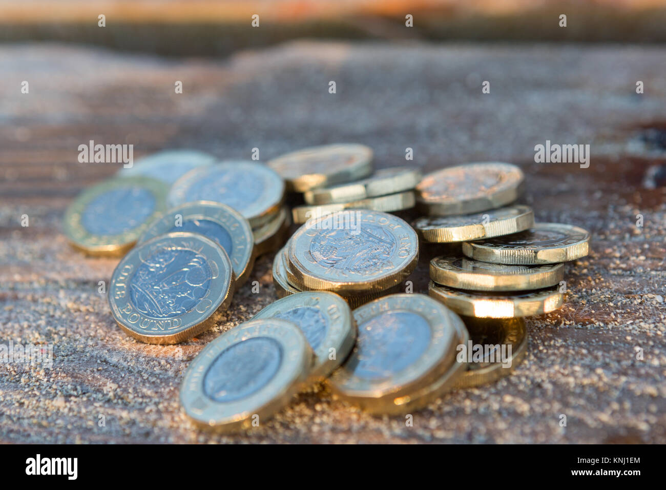 Stapel der Neue Britische Pfund Münzen auf dem Holz. Neue Pfund in einer warmen Sunrise Licht. Stockfoto