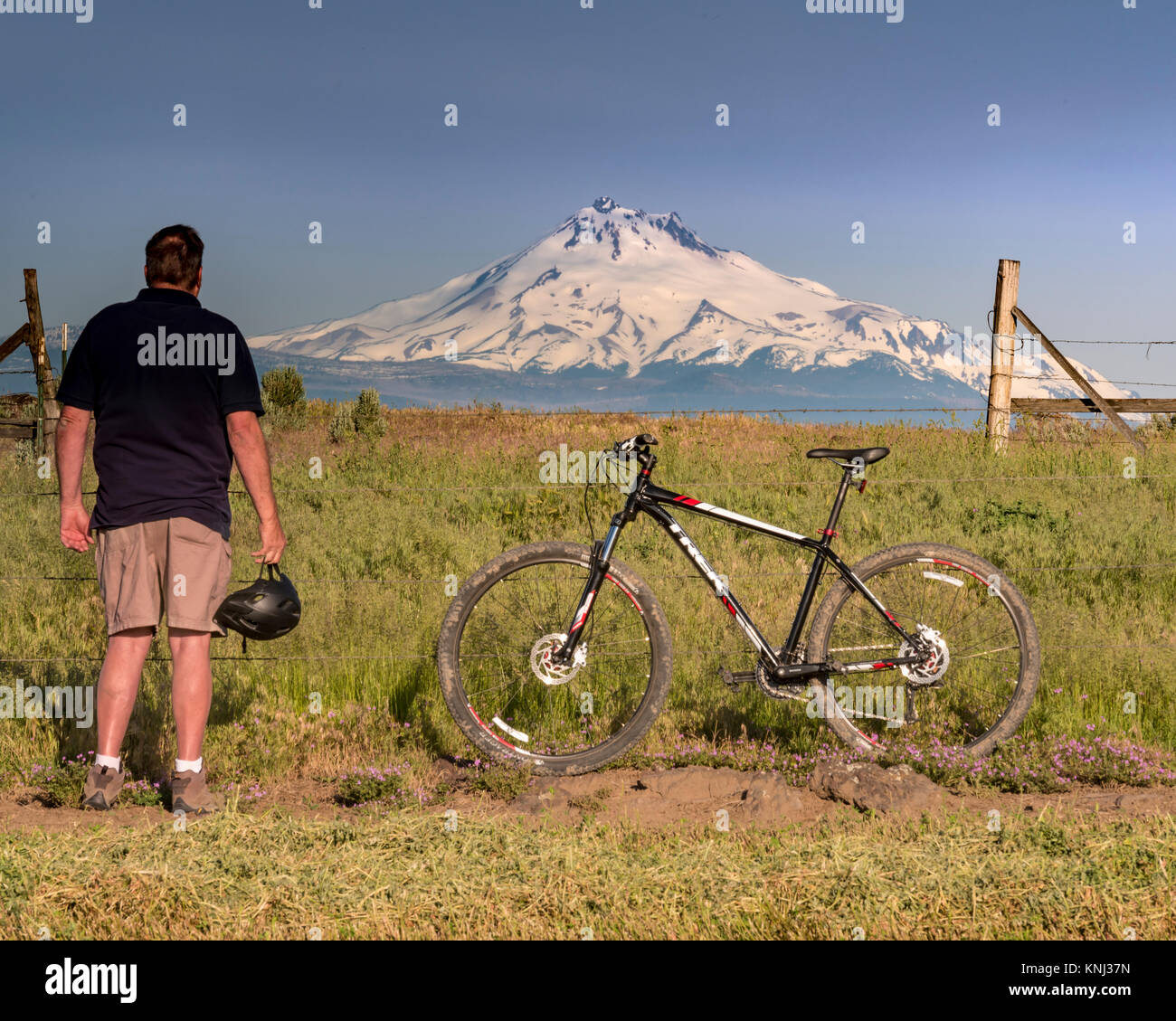 Seitenansicht des Mountainbike mit einem erwachsenen Mann mit Blick auf die Größe eines schneebedeckten Berg Stockfoto