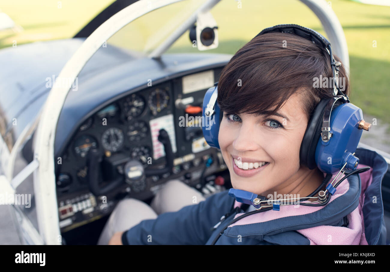 Lächelnd weibliche Piloten in der Light aircraft Cockpit, sie trägt aviator Headset und Kamera Stockfoto