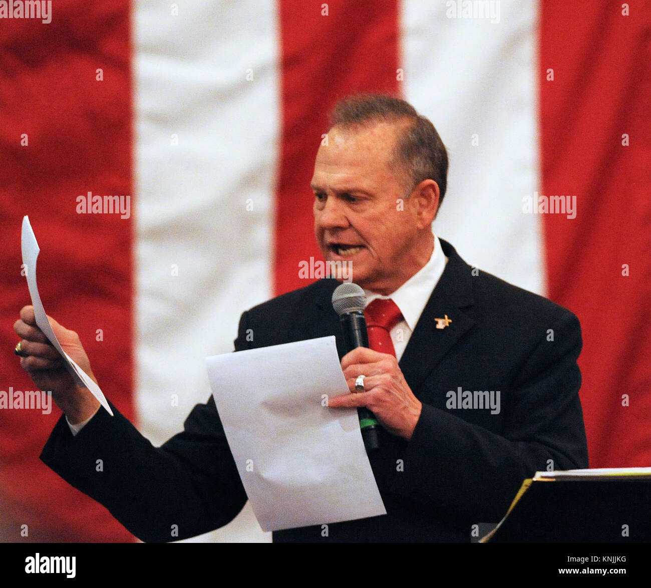 Dezember 11, 2017 - Midland City, Alabama, United States - Richter Roy Moore werden Kopien der Nachrichten Berichte über ihn, dass er Streitigkeiten während einer Rede auf einer Kundgebung am 11. Dezember 2017 in Jordanien der Aktivität Scheune in Midland City, Alabama einen Tag vor eine spezielle Wahl für einen US-Senat Sitz. Trotz der Behauptungen, dass Moore Jugendmädchen verfolgt, als er in den Dreißigern war, Umfragen zeigen Moore vor seinem demokratischen Gegner, Doug Jones. (Paul Hennessy/Alamy) Stockfoto