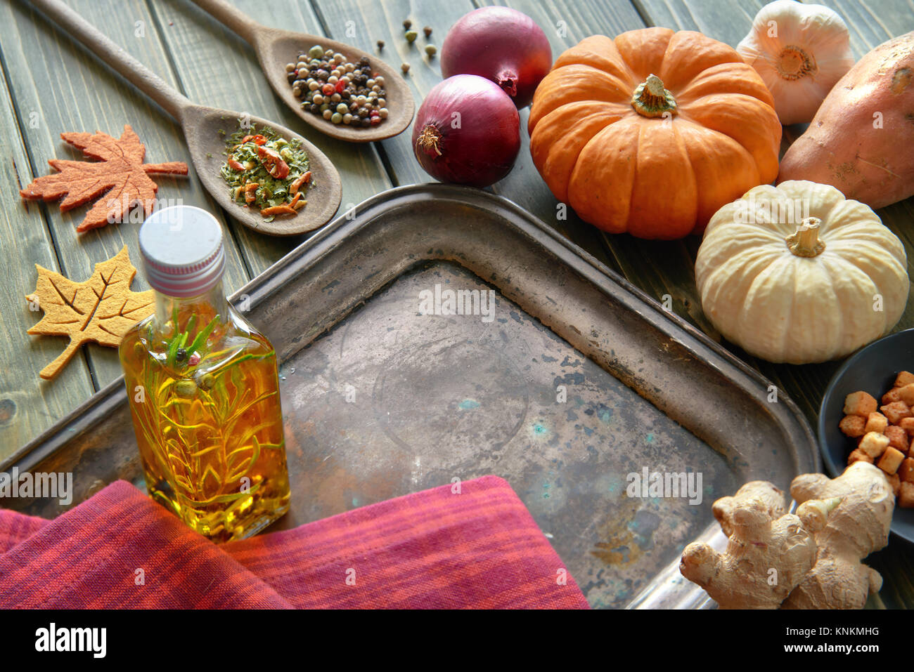 Herbst kochen Hintergrund mit Leerzeichen in der Mitte. Kürbis, Zwiebel, Ingwer, Olivenöl, Gewürze und Kartoffel auf Holz. Stockfoto