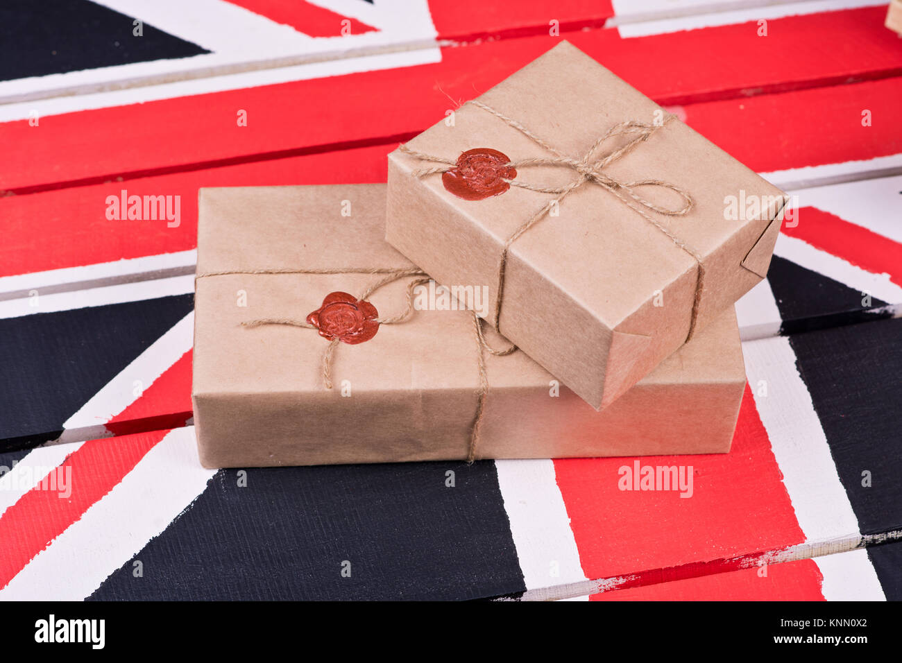 Boxen, eingewickelt in Handwerk Papier, mit packthread mit einem Wafer auf dem Hintergrund eines hölzernen Leuchter auf einem farbigen hölzernen Schreibtisch behoben. Stockfoto