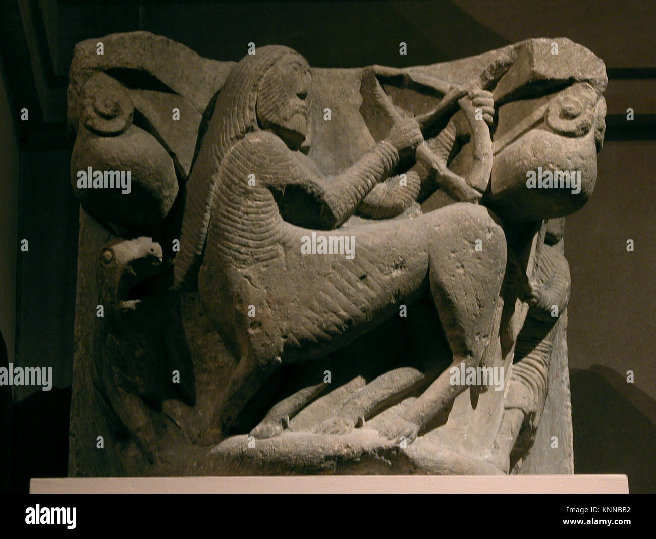 Steinhauptstadt, die einen Zentauren darstellt, der gegen einen Mann kämpft, der mit Pfeil und Bogen bewaffnet ist, und die mythologische Szene im plastischen Relief veranschaulicht. Stockfoto