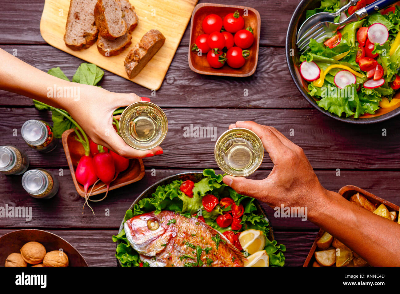 Menschen die Hände toasten über Holztisch mit farbenfrohen Speisen Stockfoto