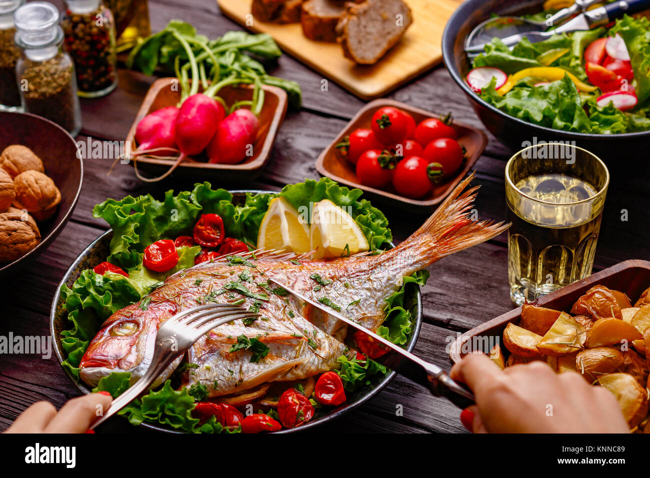 Frau essen gegrillter Fisch aus Tabelle mit farbenfrohen Speisen Stockfoto