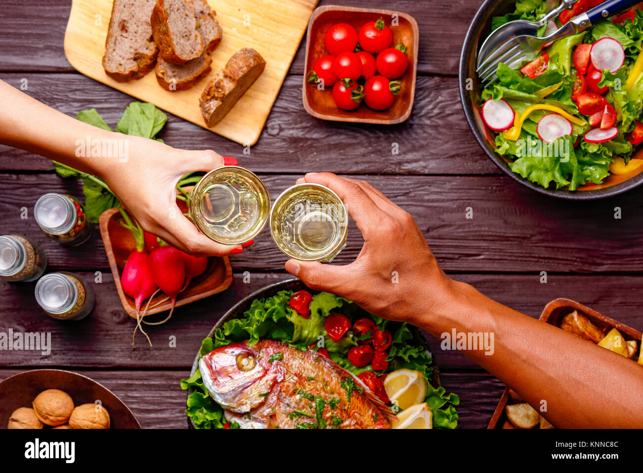 Menschen die Hände toasten über Holztisch mit farbenfrohen Speisen Stockfoto