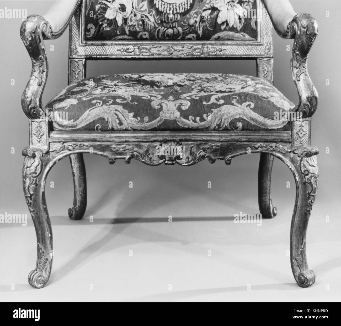 Ein französischer Sessel (Fauteuil) aus dem ersten Viertel des 18. Jahrhunderts, geschnitztes und vergoldetes Buchenholz mit Wolle Aubusson Wandteppichen, 47 1/2 x 27 1/2 x 21 5/8 cm, Teil der MET-Sammlung, repräsentativ für die französische dekorative Kunst und Möbelkunst des 18. Jahrhunderts. Stockfoto