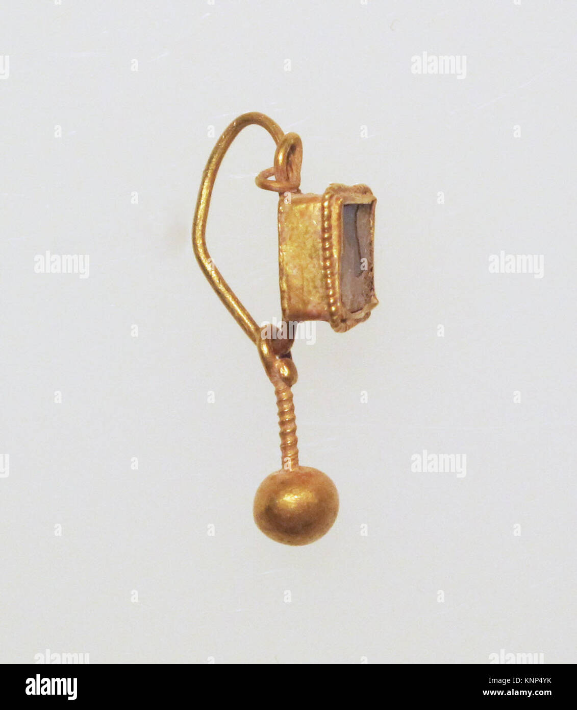 Dieser Ohrring enthält einen Kugelanhänger mit Pasteinfarbenfassung, der ein altes Schmuckdesign und dekorative Metallarbeiten demonstriert, die in der MET aufbewahrt werden. Stockfoto