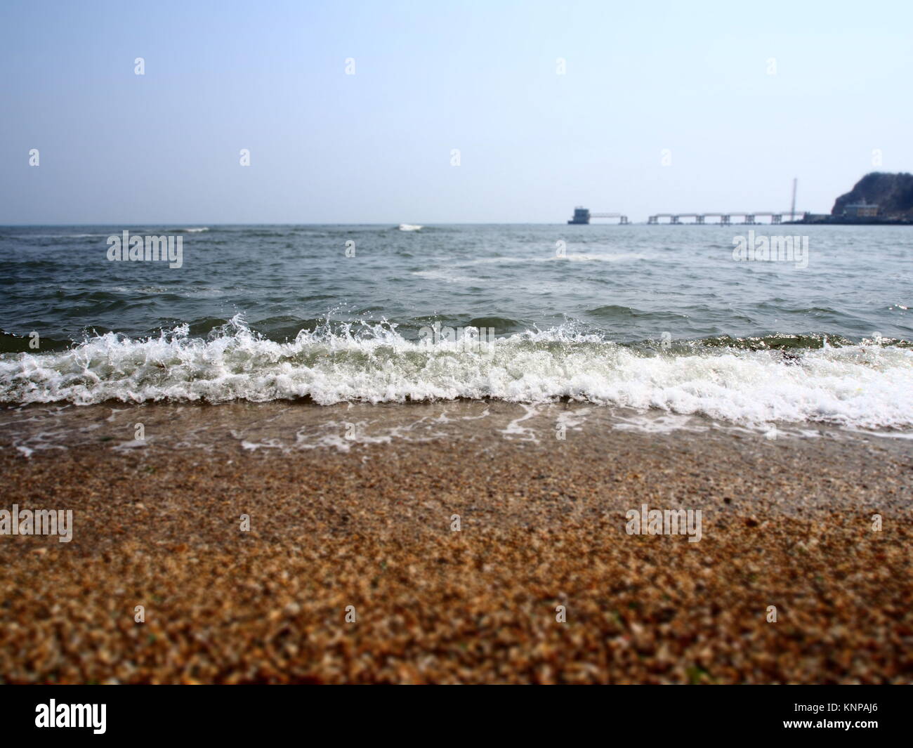 Schaumige Wellen am Ufer in Dalian, China. Stockfoto