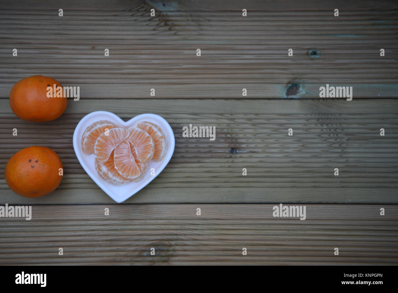 Farbe essen Fotografie Bild des gesunden Orangen Obst in Liebe Herz Form weißer Teller und glückliches Lächeln auf die Frucht auf Holz Hintergrund mit Platz gezogen Stockfoto