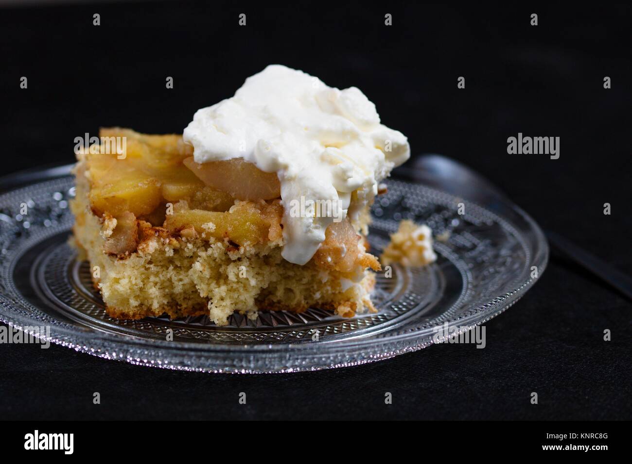 Schwamm Apfelkuchen mit Sahne auf der Glasplatte und der schwarze Hintergrund Stockfoto