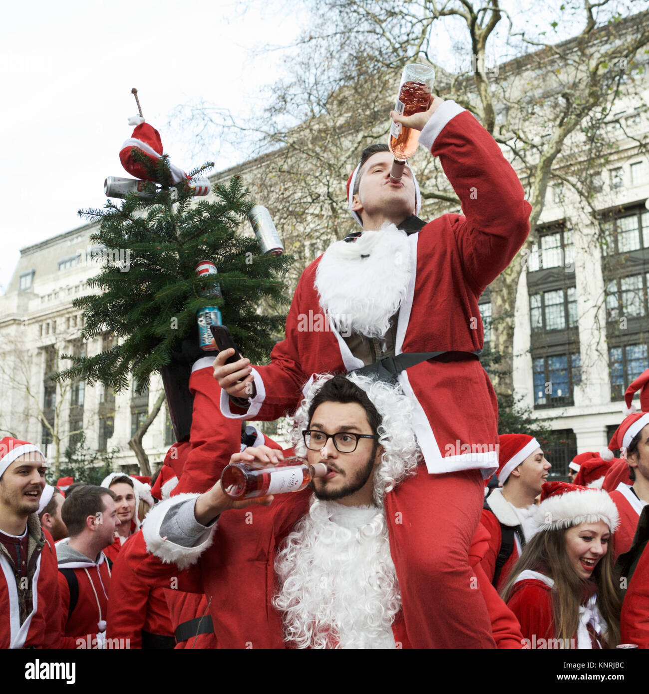 Santacon London, Großbritannien. Zwei Santas, die Alkohol trinken. Weihnachtsstimmung. Weihnachten Alkohol trinken. Millennials trinken Alkohol. Weihnachtsdrink. Stockfoto