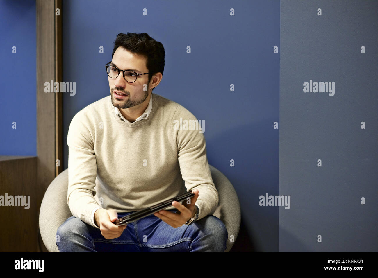 Latino Geschäftsmann mit einem mobilen Gerät in einem informellen Treffen in einem modernen Büro mit Platz für Kopie Stockfoto