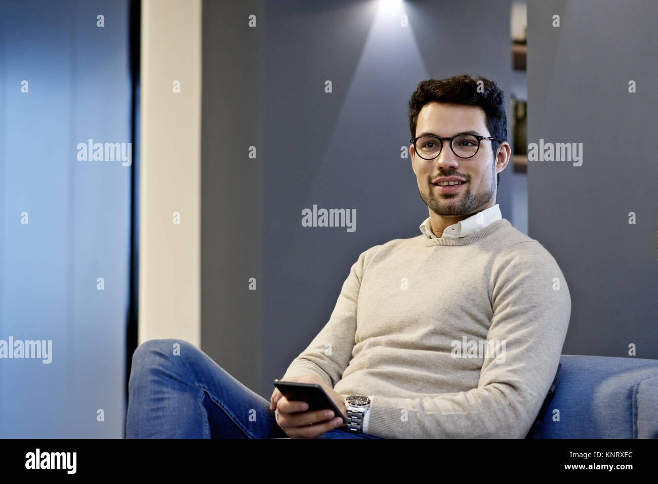 Latino Geschäftsmann mit einem mobilen Gerät in einem informellen Treffen in einem modernen Büro mit Platz für Kopie Stockfoto