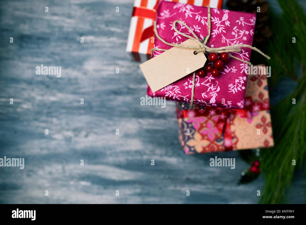 High-Angle Shot von einige gemütliche Weihnachten Geschenke in verschiedenen schöne Papiere gewickelt und mit Bändern und Streicher in verschiedenen Farben auf einem urigen Grau w gebunden Stockfoto
