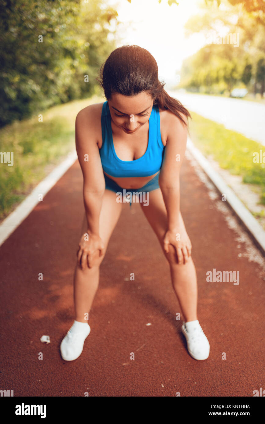 Junge sportliche Frau ausruhen nach dem Joggen an der Tartanbahn. Stockfoto