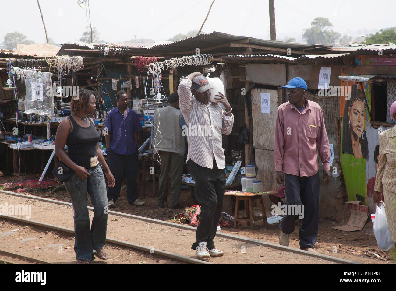 Menschen, die mit dem Einkaufen durch die Slums von Kibera in Nairobi, Kenia, Ostafrika nach Hause gehen Stockfoto