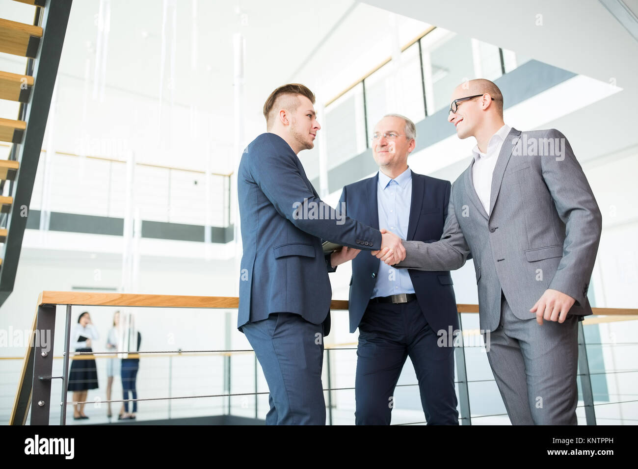 Low Angle View der Unternehmer die Hände schütteln, während sie durch Geländer stehend im Büro Stockfoto