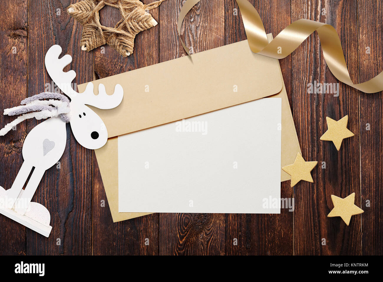 Weihnachten mockup Umschlag mit leerem Papier auf braunem Holz- Hintergrund. Brief an den Weihnachtsmann. Weihnachten Winter Einstellung - Sterne, Elche, Farbband Stockfoto