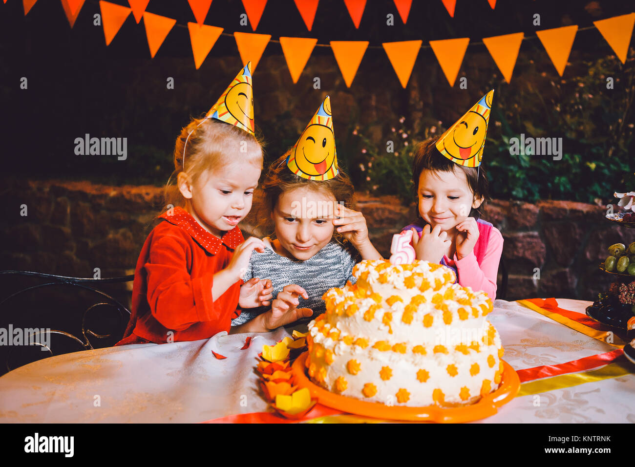 Kindergeburtstage. Drei fröhliche Kinder Mädchen Kuchen essen, mit ihren Händen und Verschmieren ihr Gesicht. Spaß und festliche Stimmung in der Dekorierten c Stockfoto